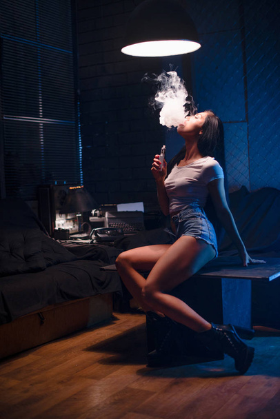 Frau dampft. sexy Brünette mit elektronischer Zigarette. Dampfkontakt - Foto, Bild