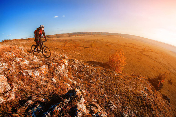 Ciclista montando en bicicleta en el sendero rocoso de montaña al atardecer. Deportes extremos
 - Foto, Imagen