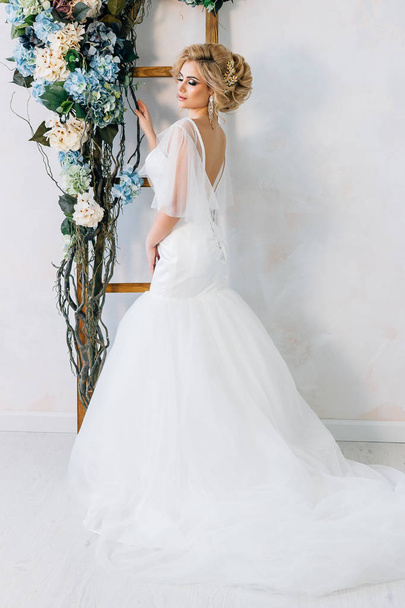 The bride stands on a white wall background - Zdjęcie, obraz