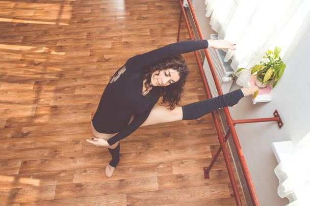 Женщина разминает ноги у балетной скамейки
 - Фото, изображение