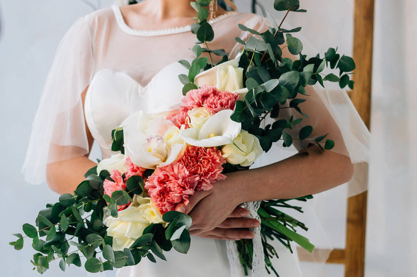 Brautstrauß in weißem Brautkleid in den Händen der schönen Braut - Foto, Bild