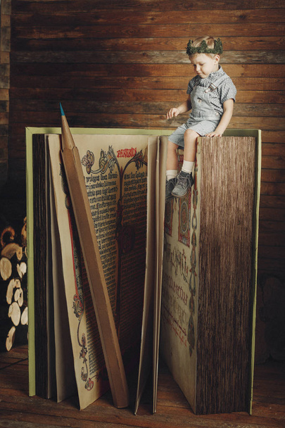 Μικρό αγόρι διαβάζοντας ένα βιβλίο, μελέτη, σύμβολο γνώσης, βιβλιόφιλος. - Φωτογραφία, εικόνα