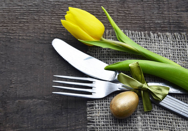 Easter table setting with spring yellow tulip,egg and cutlery on old wooden background with copy space. - Fotoğraf, Görsel