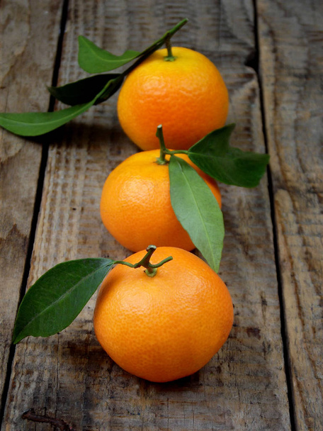 three ripe tangerine on a wooden background. selective focus. - Photo, Image