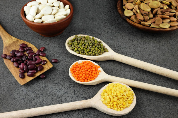 Různé druhy fazole a čočka v dřevěné misky a lžičky. - Fotografie, Obrázek