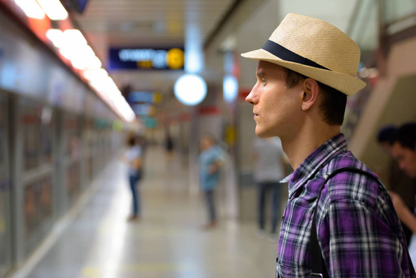 Το προφίλ άποψη για τον άνθρωπο νεαρό όμορφος τουριστικός περιμένοντας το τρένο  - Φωτογραφία, εικόνα