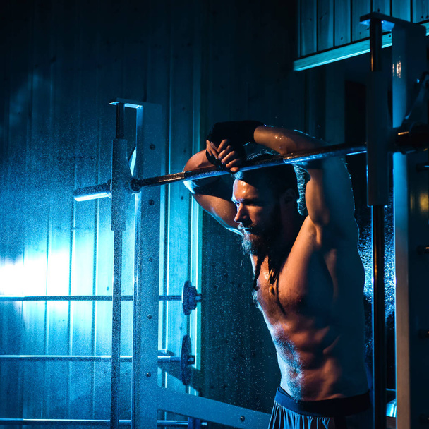 Красивый мужчина с большими мускулами, позирует перед камерой в спортзале - Фото, изображение