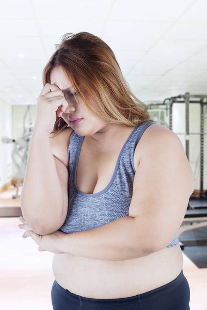 Stressful fat woman in fitness center - 写真・画像