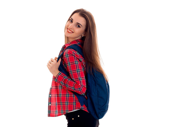 young cute girl in a Plaid Shirt and with a Briefcase on the back stands sideways and smiling - Zdjęcie, obraz
