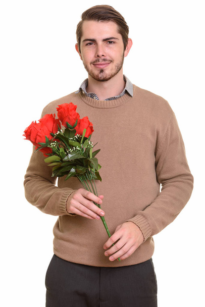 Młody przystojny kaukaski mężczyzna gospodarstwie czerwone róże gotowe do Valenti - Zdjęcie, obraz