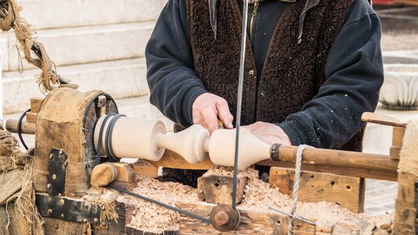 Um artesão esculpe um pedaço de madeira usando um torno manual
. - Foto, Imagem