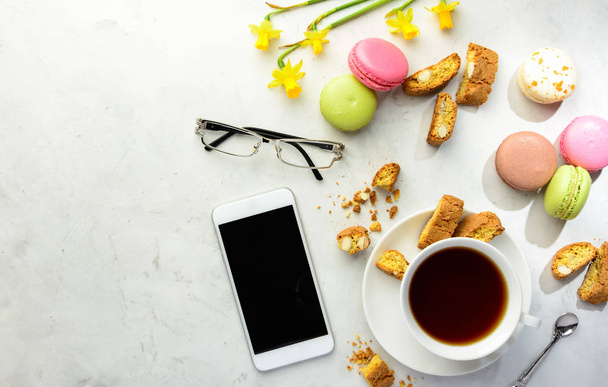 Chá com biscoitos, macaroons e smartphone com óculos
  - Foto, Imagem