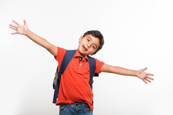 indian cute kid or boy leaving or going to school with small school bag, isolated over white background - Foto, imagen