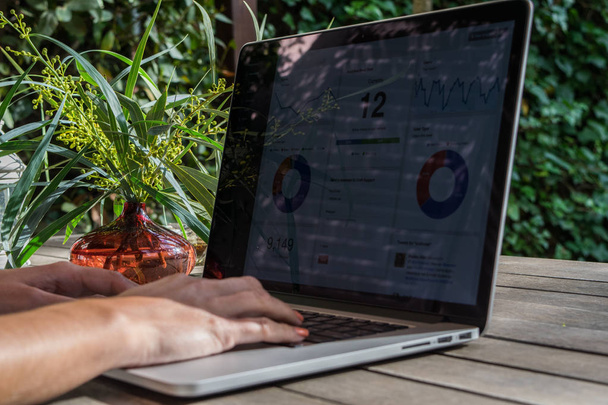 Vrouw handen laptop met analytische grafiek op Bureau in de tuin, werken aan verse lucht, freelancer - Foto, afbeelding