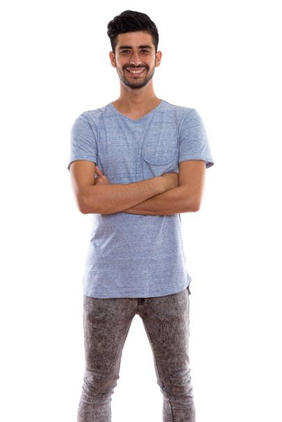 Studio shot of young happy Persian man smiling and standing with - Фото, зображення