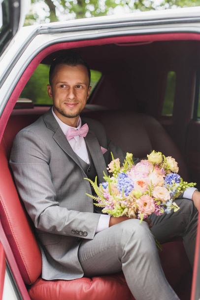 Sposo con bouquet nella macchina nuziale
 - Foto, immagini