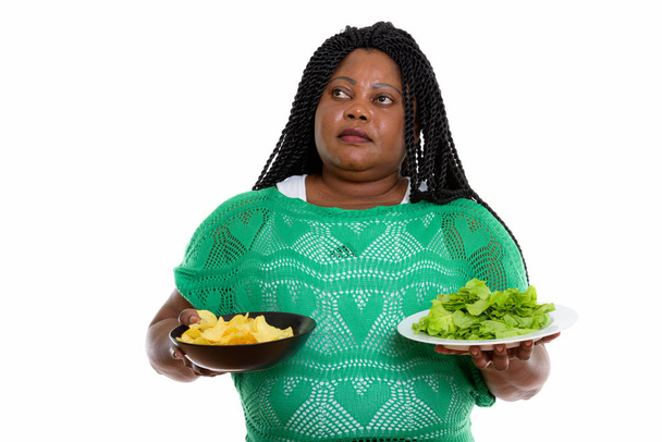 Thoughtful fat black African woman holding bowl of potato chips  - Valokuva, kuva
