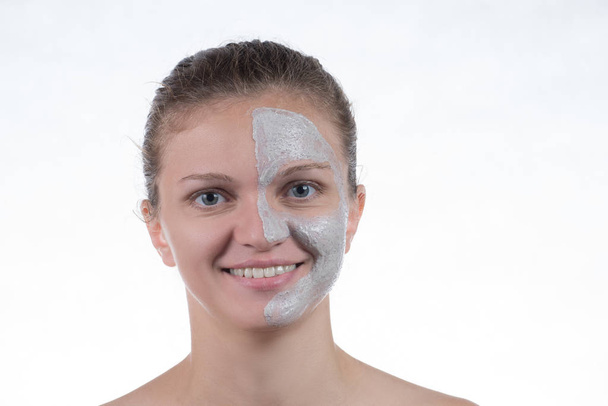 Cosmetic mask of gray clay with scrub on the face of a young gir - Photo, Image