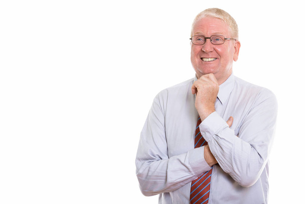Studio shot of happy mature businessman smiling while thinking a - Foto, immagini