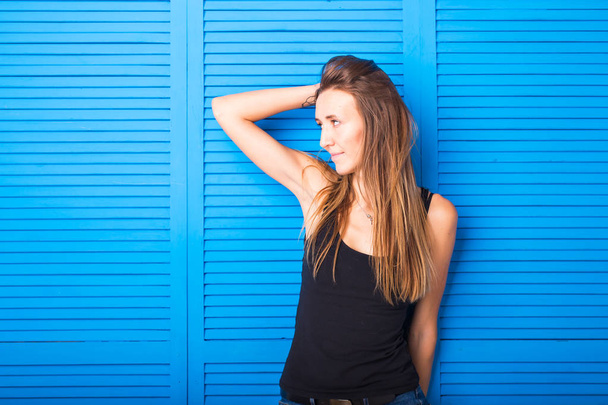 mooie vrolijke tiener meisje in zwarte top over blauwe achtergrond - Foto, afbeelding