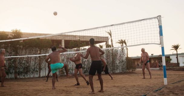 男性の白人、アラブ人、アフリカ人がビーチでバレーボール - 写真・画像