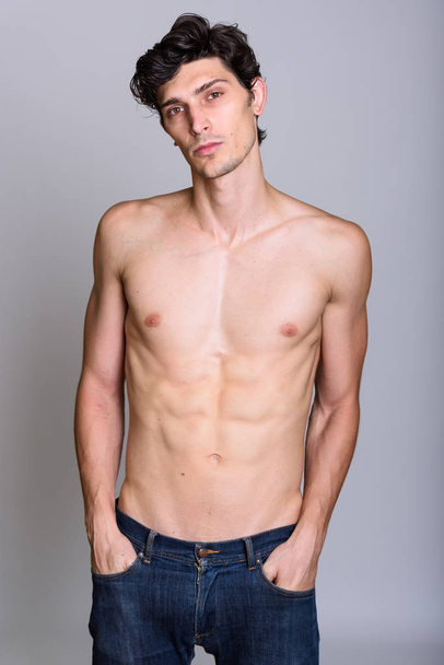Studio shot of young handsome man shirtless with hands on pocket - Foto, imagen