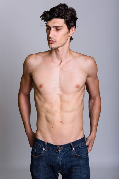 Studio shot of young handsome man standing while looking down sh - Photo, Image
