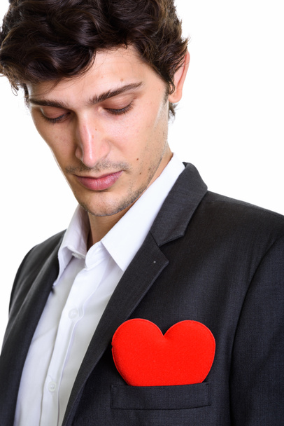 Primer plano de joven hombre de negocios guapo mirando el corazón rojo en c
 - Foto, imagen
