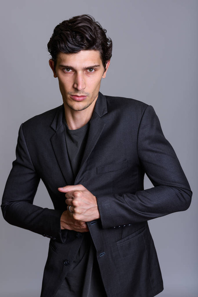 Студийный снимок молодого привлекательного бизнесмена, держащего куртку против
 - Фото, изображение