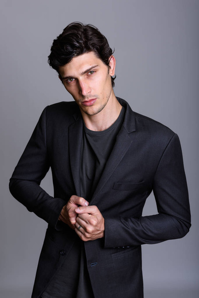 Studio shot of young handsome businessman holding jacket against - Foto, immagini