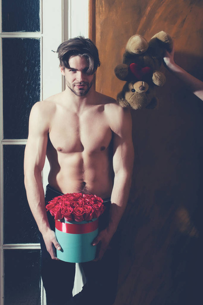 bearded muscular man with sexy body holds red rose box - Photo, Image
