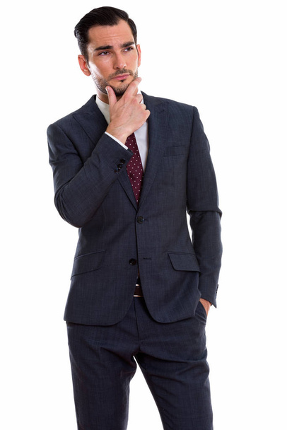 Студийный кадр молодого привлекательного бизнесмена, стоящего и размышляющего
 - Фото, изображение