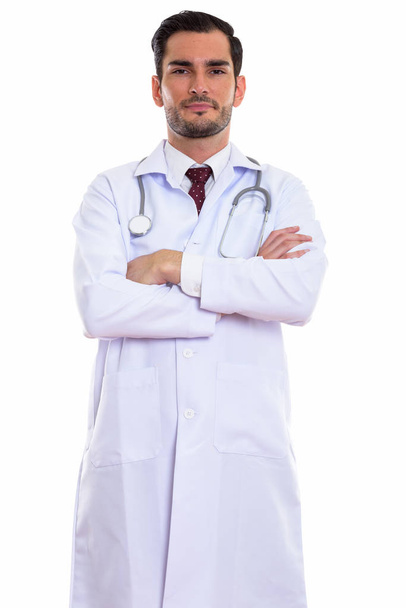 Studio shot of young handsome man doctor standing with arms cros - Фото, изображение