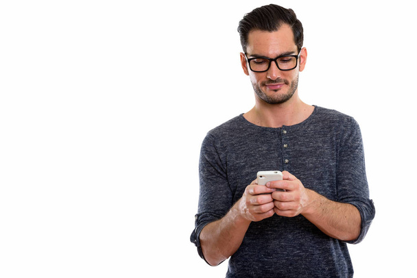 Studio shot of young handsome man using mobile phone while weari - Fotoğraf, Görsel
