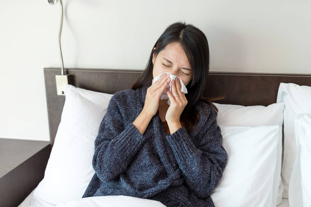 Woman feeling sick and sneeze on bed - Foto, imagen