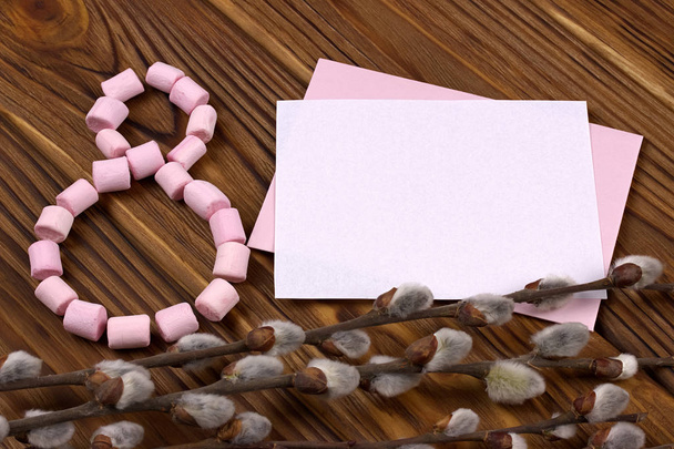 La figura-ocho forrada con malvavisco rosa caja de regalo verde con ramas de resorte de cinta púrpura con brotes de papel con espacio para el texto sobre un fondo marrón de madera
 - Foto, Imagen