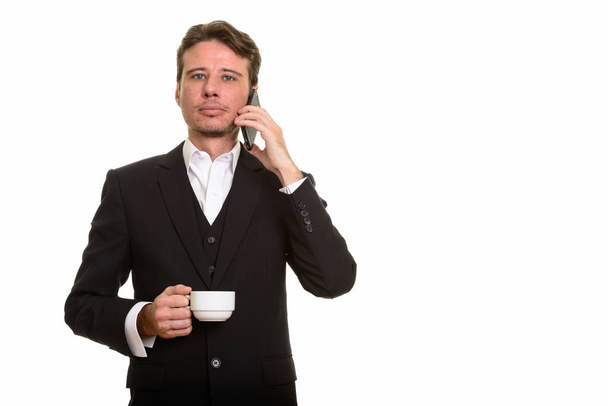 Handsome Caucasian businessman talking on mobile phone while hol - Фото, изображение