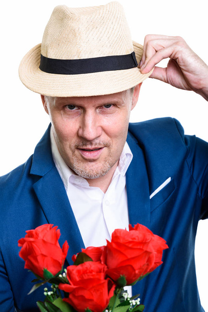 Close up of mature businessman holding hat and red roses ready f - Photo, Image