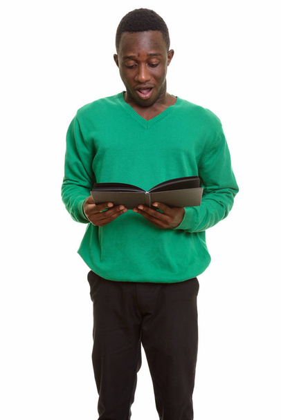 Genç yakışıklı Afrikalı adam kitap okurken şok olmuş görünüyor.  - Fotoğraf, Görsel
