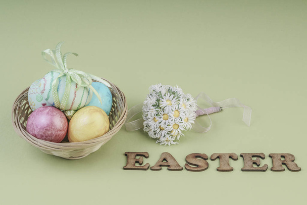 Colorful easter eggs in a basket on green - Fotó, kép