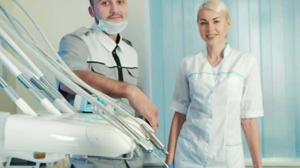 Dentist with his assistant stand near happy patient in special chair. - Πλάνα, βίντεο