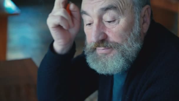 Emotional tired old man sitting, smoking cigarette thinking, scratching ear 4K - Filmati, video
