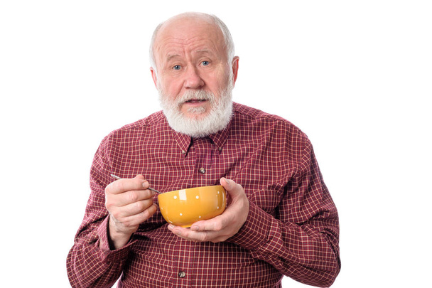 Vanhempi mies syö oragne kulho, eristetty valkoinen
 - Valokuva, kuva