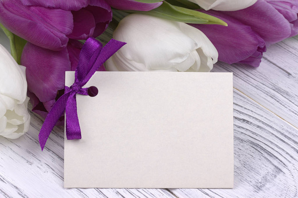 Tulipanes morados y blancos con papel blanco sobre fondo de madera blanca. Día de la Mujer. 8 de marzo
. - Foto, Imagen
