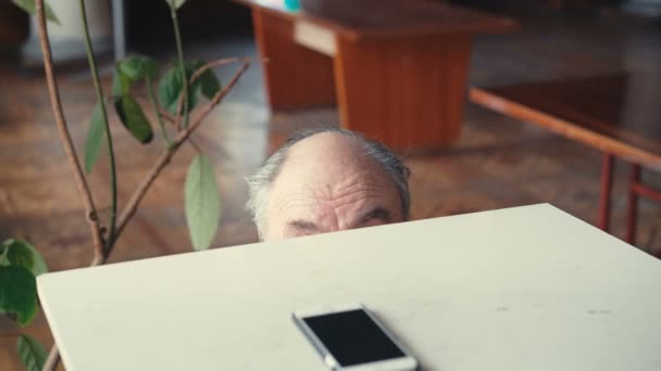 Old man attaining phone and considering emotionally in 4K - Video, Çekim