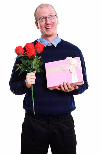 思慮深い幸せな男は赤いバラを押しながら笑みを浮かべて、bo のギフト - 写真・画像