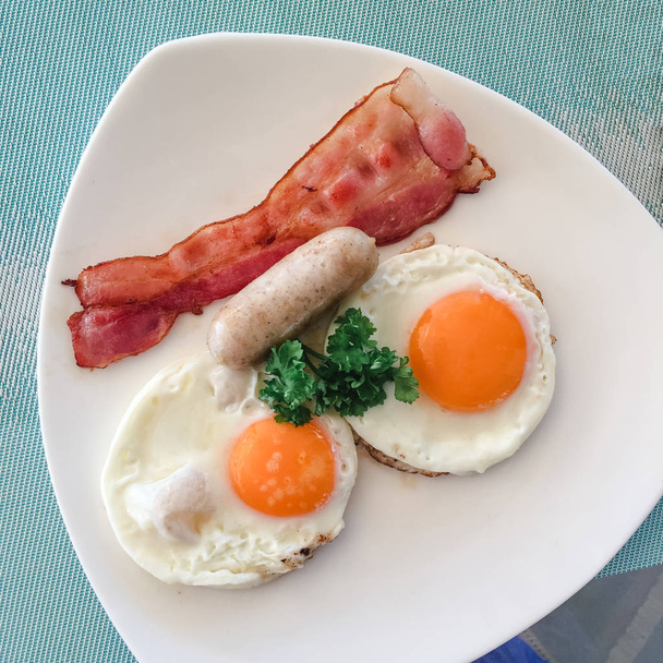 Desayuno americano. delicioso desayuno para uno. Manos de mujer cortando huevo cuchillo en una sartén. Vista desde arriba. Huevos fritos. Vista superior
. - Foto, Imagen