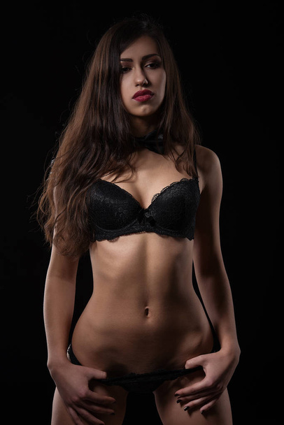 Seductive young woman posing in black sexy lingerie. - 写真・画像