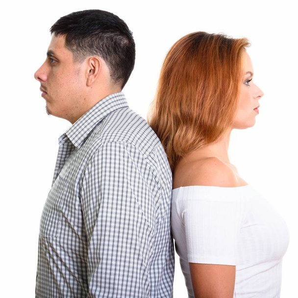 Studio shot of young couple with backs against each other - Foto, Imagen