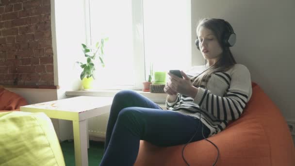 Teenager girl lisening to music and looking at the phone screen - Video, Çekim